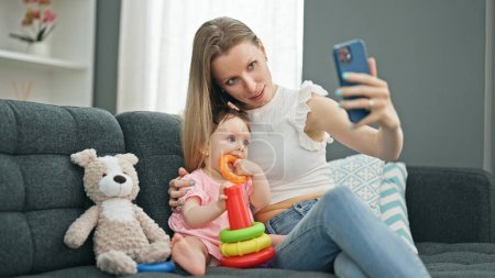 Téléchargez les photos : Mère et fille font selfie par smartphone tout en jouant avec des cerceaux à la maison - en image libre de droit