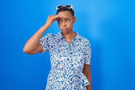 Photo for African american woman standing over blue background worried and stressed about a problem with hand on forehead, nervous and anxious for crisis - Royalty Free Image