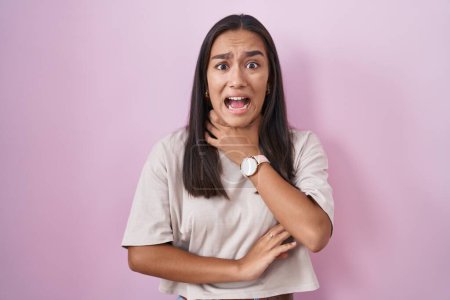 Photo for Young hispanic woman standing over pink background shouting suffocate because painful strangle. health problem. asphyxiate and suicide concept. - Royalty Free Image