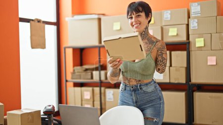 Téléchargez les photos : Hispanique femme avec amputé bras commerce électronique entreprise travailleur tenant paquet souriant au bureau - en image libre de droit