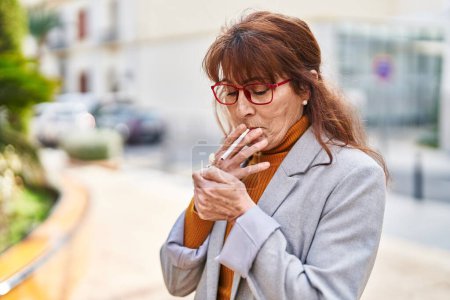 Foto de Mujer de mediana edad negocio ejecutivo fumar cigarrillo en el parque - Imagen libre de derechos