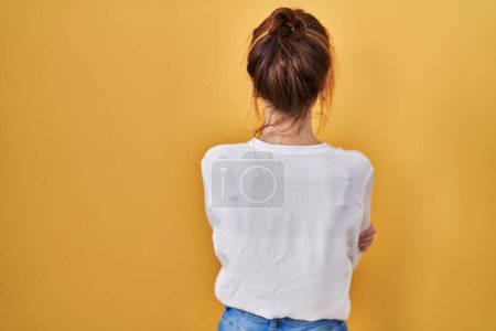 Photo for Young beautiful woman wearing casual shirt over yellow background standing backwards looking away with crossed arms - Royalty Free Image