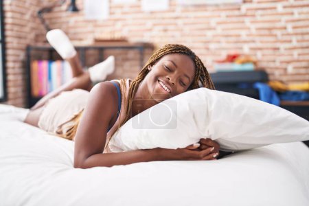 Photo for African american woman hugging pillow lying on bed at bedroom - Royalty Free Image