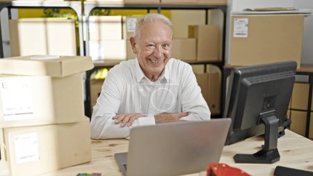Téléchargez les photos : Homme âgé aux cheveux gris commerçant en ligne travailleur d'affaires utilisant un ordinateur portable assis avec les bras croisés geste au bureau - en image libre de droit