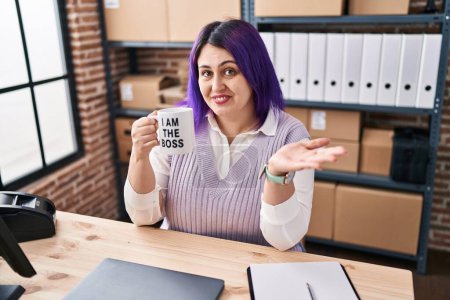 Photo for Plus size woman wit purple hair working at small business ecommerce holding i am the boss cup celebrating achievement with happy smile and winner expression with raised hand - Royalty Free Image
