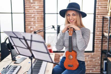 Photo for Young woman artist holding ukelele at music studio - Royalty Free Image