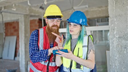 Photo for Man and woman builders using smartphone working at construction site - Royalty Free Image