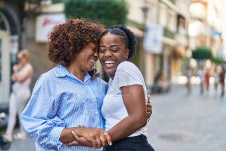 Téléchargez les photos : Les femmes afro-américaines mère et fille se câlinent dans la rue - en image libre de droit