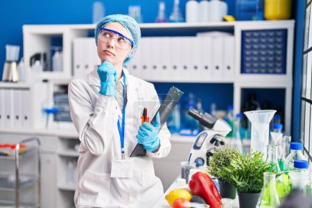 Photo for Beautiful woman working at scientist laboratory with food serious face thinking about question with hand on chin, thoughtful about confusing idea - Royalty Free Image