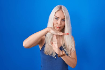 Téléchargez les photos : Femme caucasienne debout sur fond bleu faisant un geste avec les mains, frustré et sérieux visage - en image libre de droit