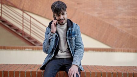 Photo for Young hispanic man speaking on the phone at street - Royalty Free Image