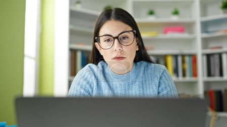 Téléchargez les photos : Jeune étudiante hispanique utilisant un ordinateur portable étudiant à l'université de la bibliothèque - en image libre de droit