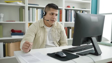 Photo for Young hispanic man student having video call writing on document at library university - Royalty Free Image