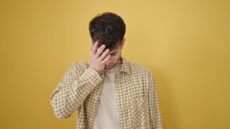 Photo for Young hispanic man standing with upset expression covering face over isolated yellow background - Royalty Free Image