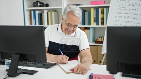 Foto de Hombre de mediana edad con profesor de pelo gris usando notas de computación en el aula universitaria - Imagen libre de derechos