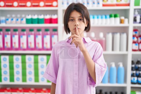 Téléchargez les photos : Jeune fille à la pharmacie pharmacie demandant à se taire avec le doigt sur les lèvres. silence et concept secret. - en image libre de droit