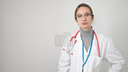 Foto de Mujer joven caucásica médico de pie con expresión seria sobre fondo blanco aislado - Imagen libre de derechos