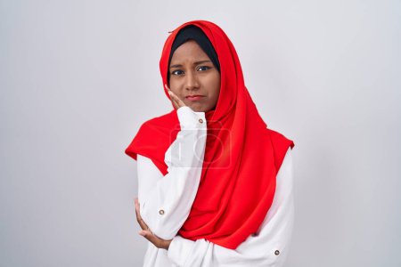 Foto de Mujer árabe joven que usa bufanda islámica tradicional hiyab pensando que se ve cansada y aburrida con problemas de depresión con los brazos cruzados. - Imagen libre de derechos
