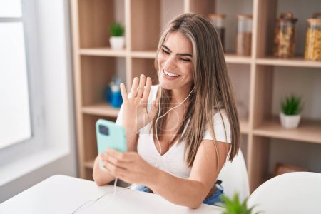 Photo for Young beautiful woman doing video call with smartphone looking positive and happy standing and smiling with a confident smile showing teeth - Royalty Free Image