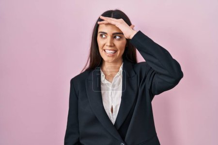 Photo for Young brunette woman wearing business style over pink background very happy and smiling looking far away with hand over head. searching concept. - Royalty Free Image