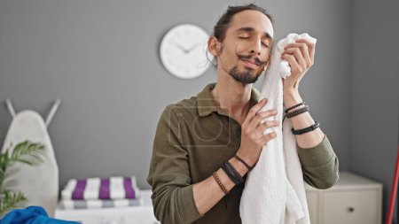 Photo for Young hispanic man smiling confident touching face with clean towel at laundry room - Royalty Free Image