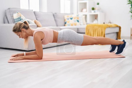 Foto de Mujer rubia joven entrenamiento core ejercicio en casa - Imagen libre de derechos