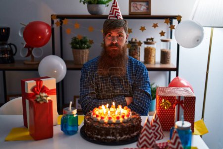 Photo for Caucasian man with long beard celebrating birthday holding big chocolate cake with serious expression on face. simple and natural looking at the camera. - Royalty Free Image