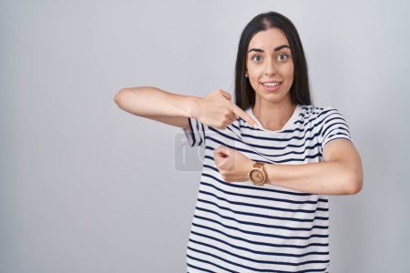 Photo for Young brunette woman wearing striped t shirt in hurry pointing to watch time, impatience, upset and angry for deadline delay - Royalty Free Image