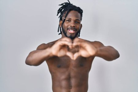 Photo for African man with dreadlocks standing shirtless over isolated background smiling in love showing heart symbol and shape with hands. romantic concept. - Royalty Free Image
