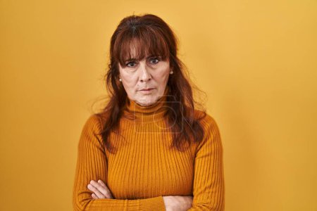 Photo for Middle age hispanic woman standing over yellow background skeptic and nervous, disapproving expression on face with crossed arms. negative person. - Royalty Free Image