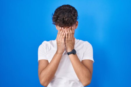 Photo for Hispanic teenager standing over blue background rubbing eyes for fatigue and headache, sleepy and tired expression. vision problem - Royalty Free Image