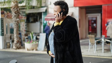 Photo for Young pregnant woman talking on smartphone smiling at street - Royalty Free Image