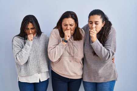 Photo for Mother and two daughters standing over blue background feeling unwell and coughing as symptom for cold or bronchitis. health care concept. - Royalty Free Image