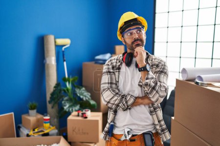 Photo for Young hispanic man with beard working at home renovation with hand on chin thinking about question, pensive expression. smiling with thoughtful face. doubt concept. - Royalty Free Image