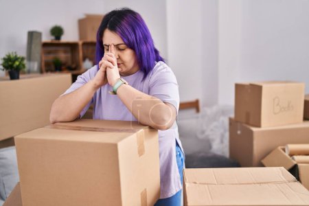 Photo for Young beautiful plus size woman stressed leaning on package at new home - Royalty Free Image