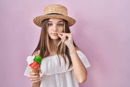 Téléchargez les photos : Adolescente tenant la bouche de crème glacée et les lèvres fermées comme zip avec les doigts. secret et silencieux, tabou parlant - en image libre de droit