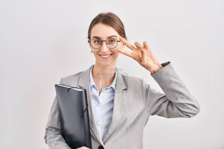Photo for Young caucasian woman wearing business clothes and glasses doing peace symbol with fingers over face, smiling cheerful showing victory - Royalty Free Image