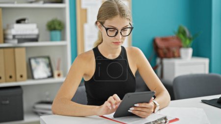 Téléchargez les photos : Jeune femme blonde travailleuse d'affaires utilisant un pavé tactile au bureau - en image libre de droit