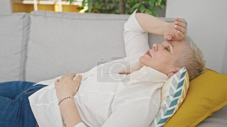 Photo for Middle age grey-haired woman lying on sofa tired at home - Royalty Free Image