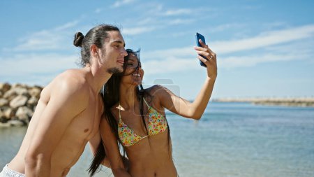 Foto de Hombre y mujer turista pareja de pie juntos hacer selfie por teléfono inteligente en la playa - Imagen libre de derechos