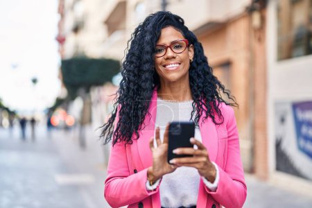 Téléchargez les photos : Femme afro-américaine cadre en utilisant smartphone à la rue - en image libre de droit