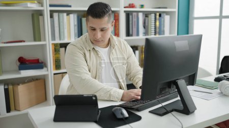 Foto de Joven estudiante hispano usando computadora y touchpad estudiando en la universidad de la biblioteca - Imagen libre de derechos