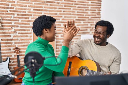 Photo for African american man and woman music group high five with hands raised up at music studio - Royalty Free Image
