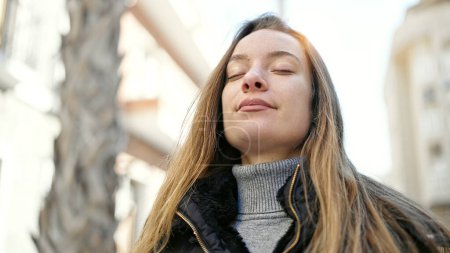 Téléchargez les photos : Jeune femme caucasienne respirant les yeux fermés à la rue - en image libre de droit