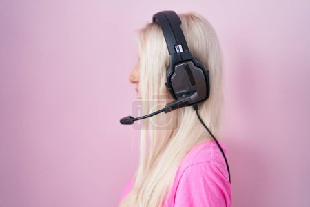 Foto de Mujer caucásica escuchando música usando auriculares mirando al costado, pose de perfil relajado con cara natural con sonrisa confiada. - Imagen libre de derechos