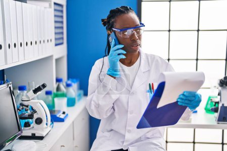 Photo for African american woman scientist reading document at laboratory - Royalty Free Image