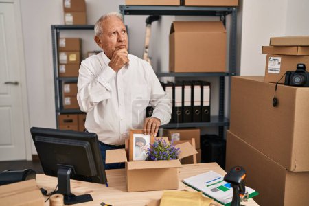 Photo for Senior man with grey hair working at small business ecommerce serious face thinking about question with hand on chin, thoughtful about confusing idea - Royalty Free Image