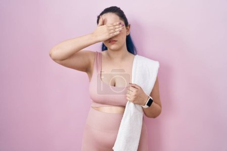 Photo for Young modern girl with blue hair wearing sportswear over pink background covering eyes with hand, looking serious and sad. sightless, hiding and rejection concept - Royalty Free Image