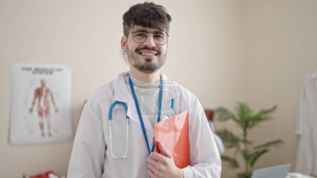 Photo for Young hispanic man doctor smiling confident standing at clinic - Royalty Free Image