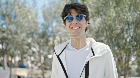 Foto de Young hispanic man smiling confident wearing sunglasses at park - Imagen libre de derechos